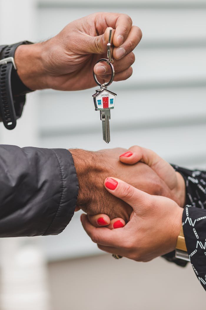 Home Close-up of a handshake with a house key, symbolizing real estate transactions.
